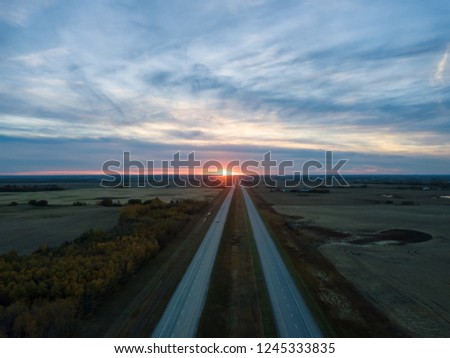 Aerial view of the Highway in the Prairies during a vibrant cloudy sunset. Taken East of Edmonton, Alberta, Canada.