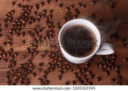 Steaming hot coffee and beans on vintage wooden table. Coffee break concept. White cup, winter drink, espresso, top view