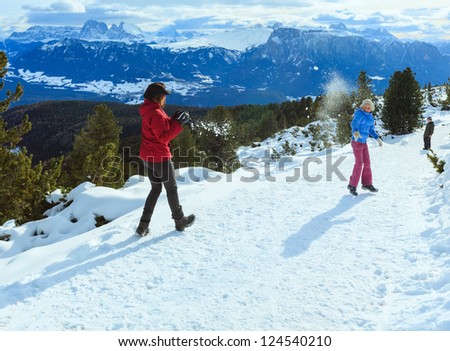 Family  (mother with  two children) plays at snowballs on winter mountain slope