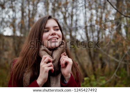 Girl with long hair in a red coat in the Park in late autumn