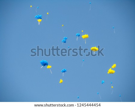 Flying yellow and blue balloons in blue sky. Bright background. Colorful festive yellow and blue balloons against the blue cloudless sky.