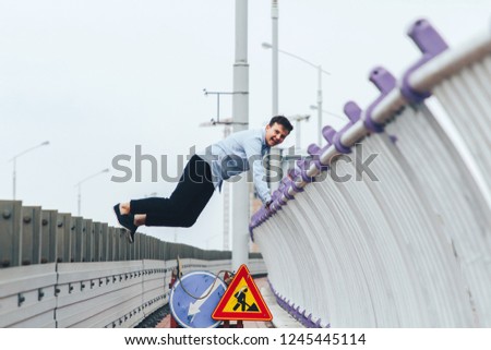 The guy hung on the bridge next to two road signs
