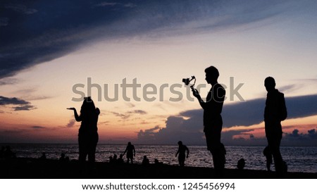 Silhouettes of tourists with technology on the background of a sunset on the sea