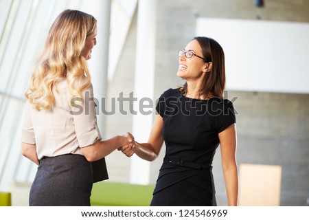 Two Businesswomen Shaking Hands In Modern Office Royalty-Free Stock Photo #124546969