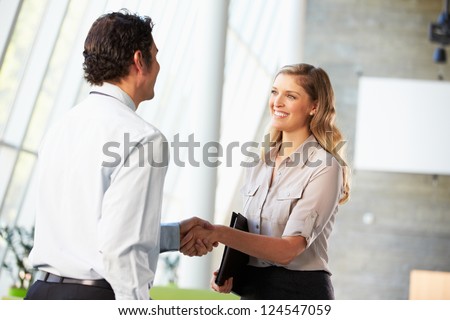 Businessman And Businesswoman Shaking Hands In Office Royalty-Free Stock Photo #124547059