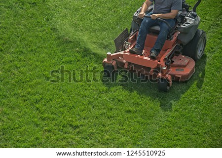 Closeup of a riding landscaper on the lawn mower cutting the grass Royalty-Free Stock Photo #1245510925