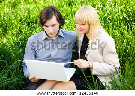 boy and girl dressd for business with laptop on the grass