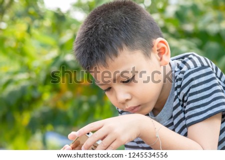 Portrait of Asian boys are playing mobile phones in park.