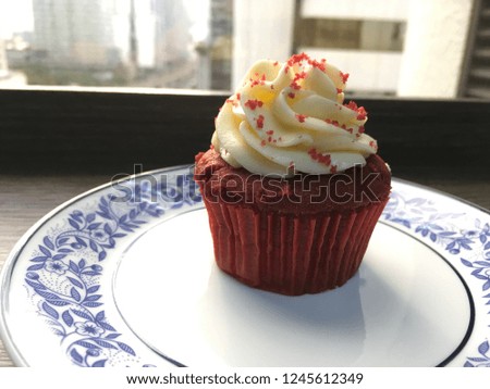 Red velvet cupcake on blue pattern white dish.