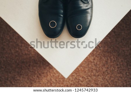 Wedding ring on the tip of men's black shoes.