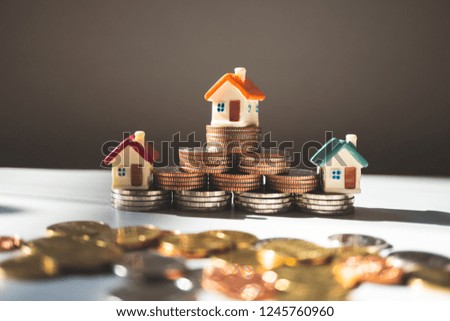 Miniature house on stack coins with sunlight using as property and financial concept