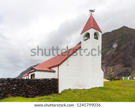 Saint Joseph's Catholic church in Edinburgh of the Seven Seas town, Tristan da Cunha, the most remote island. Red roof and bellower, a whale and cardinal direction pointer signs on top of the spire.