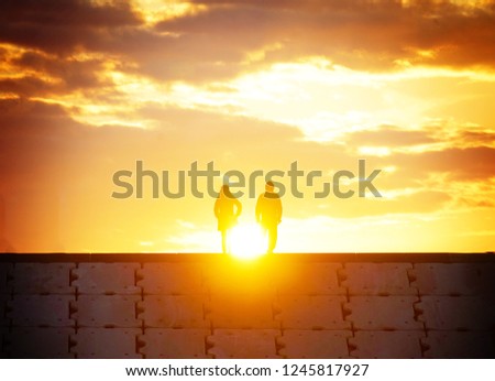 Sunrise and two people of the silhouette