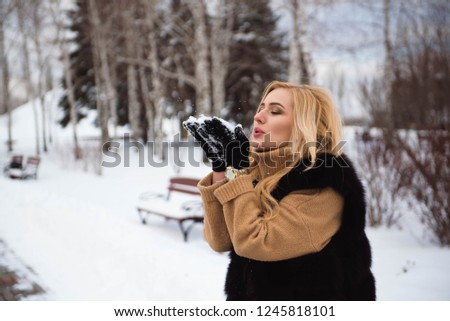 woman blowing snow in hands in slow motion