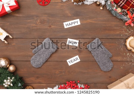 Happy new year congratulations theme mittens isolated on wooden table top view close-up