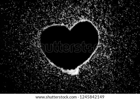 Empty love heart symbol drawing by finger on white salt powder on black background. Romantic St. Valentines Day holidays concept with place for text. Copy space.