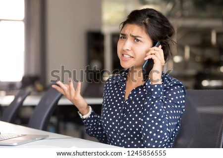 Outraged attractive Indian female employee talking by phone, arguing with client or customer, actively gesticulating, businesswoman having serious conversation on smartphone, solve business problem Royalty-Free Stock Photo #1245856555