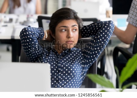 Thoughtful peaceful Indian female employee looking in distance, leaning back in chair at workplace, relaxing during break after finish hard job, tired businesswoman thinking about work, feeling bored Royalty-Free Stock Photo #1245856561
