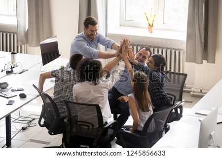 Multiracial employees team with male leader, coach giving high five at company meeting, boss with office workers celebrating business achievement, corporate success of teamwork, team building activity Royalty-Free Stock Photo #1245856633