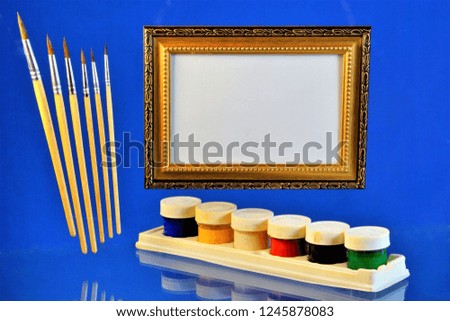 Frame for drawing or text, colorful gouache and a lot of brushes, blue background. Drawing pictures with bright colors, good for design and creativity.