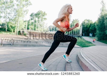 Photo of curly-haired athletic woman running through park among 