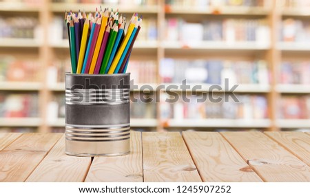 Colorful pencils in jar and red apple on table