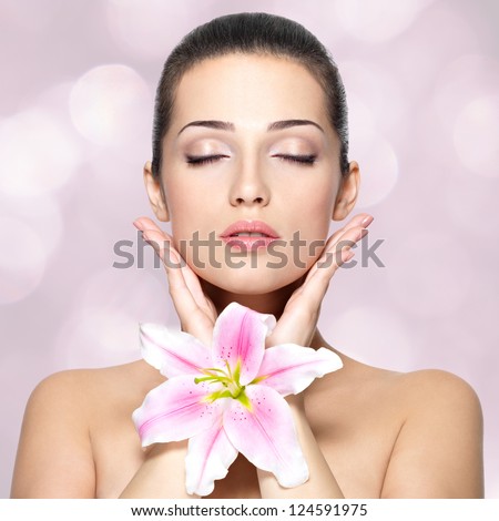 Beauty face of young woman with flower. Portrait of young woman with closed eyes. Blinking Background. Bokeh