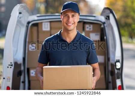 Smiling delivery man standing in front of his van Royalty-Free Stock Photo #1245922846