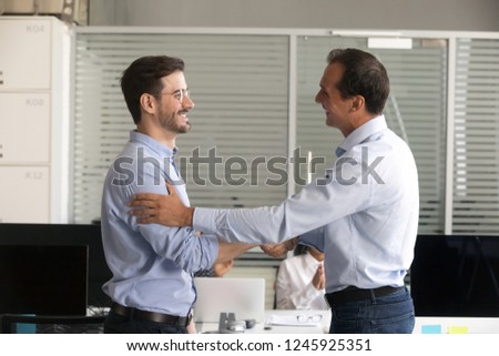 Friendly middle aged boss handshaking male successful employee, congratulate confident worker with promotion, business achievement, thank for good work results, expressing respect, rewarding Royalty-Free Stock Photo #1245925351
