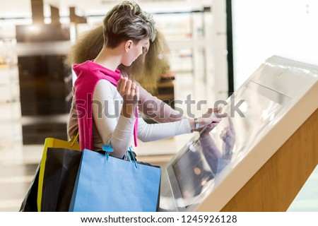 Woman use information kiosk at Galeria shopping center. Galeria is major shopping and entertainment center is located in downtown of St. Petersburg