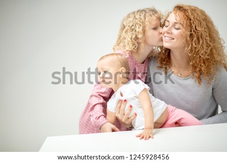 little girl with lonf curly hare loves her mother and little sister. close up photo. copy space. child's love