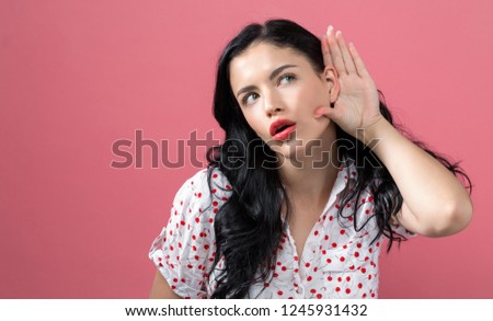 Young woman listening on a pink background