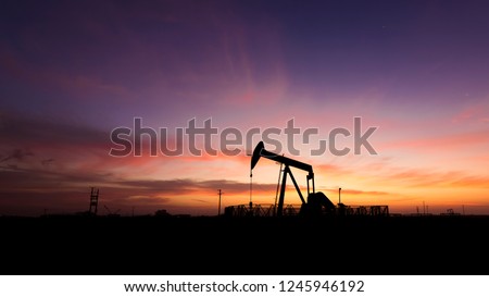 Silhouette of crude oil pump in the oilfield at sunset Royalty-Free Stock Photo #1245946192