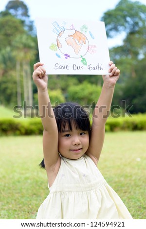 Little kid showing save our earth drawing in a park