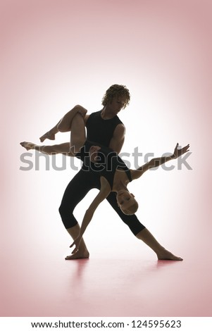 Silhouette of dancing pair posing on pink background