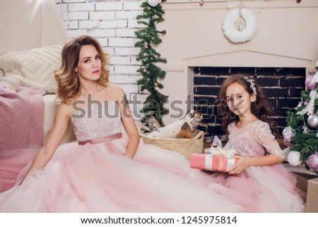 Holidays, celebration and people concept - young woman in elegant dress over christmas interior background. Image with grain mom and daughter