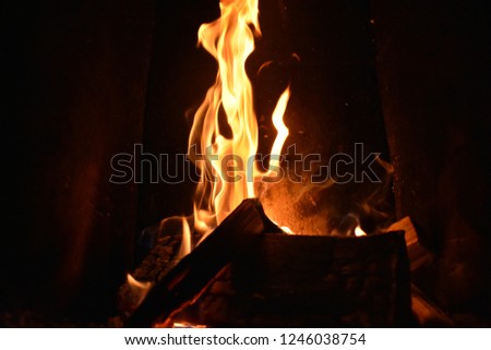 Close-up Picture of fire in a fireplace. Fire in a fireplace flames playing, cold weather outside fire collar heat warmth heater dark background.