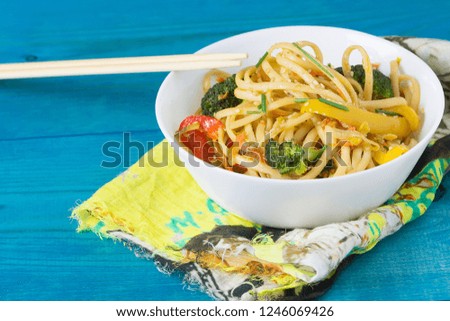 Cinese noodles. Stir fry udon noodles with vegetables on a blue wooden background, cooked in wok