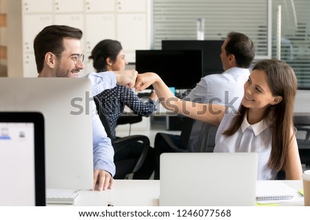Friendly smiling colleagues fist bumping at workplace, happy coworkers sharing success, young woman and man celebrating good teamwork result, satisfied by collaboration, cooperation at work, respect Royalty-Free Stock Photo #1246077568