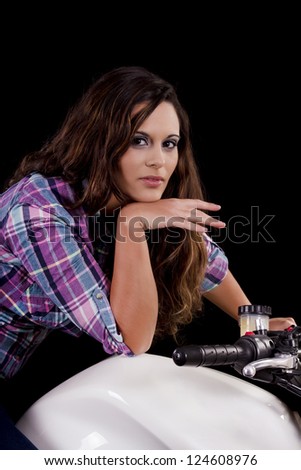 View of a beautiful young girl next to a white motorbike in a studio environment.