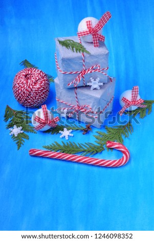 Present boxes, a candy cane, Christmas tree toys and thuja branches against the blue background. Christmas composition. Copy space