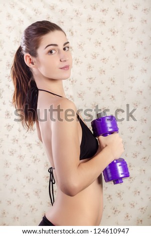 View of a beautiful young teenager in bikini with fitness weights.