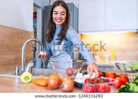 Only clean and fresh vegies for my salad. Beautiful young woman washing vegetables for salad and smiling while standing in the kitchen. Vegetables in the sink on kitchen. Fresh vegetables. Homemade 