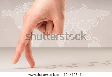 Female fingers walking with footsteps behind them and a world map in the background