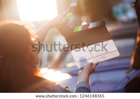 Filming on location. Woman holding a clapperboard in front of the camera, the filming process. Scene on location. Royalty-Free Stock Photo #1246148365
