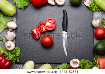 Sliced tomatoes in a blackboard and variation of fresh organic vegetables ready for cooking. Top view Royalty-Free Stock Photo #1246153531