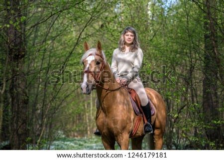 Young lady riding a horse in the spring forest.