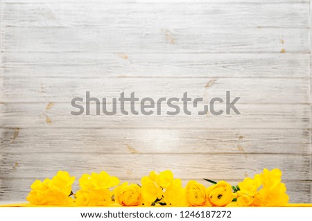 light wooden background with yellow flowers at the bottom, copy space