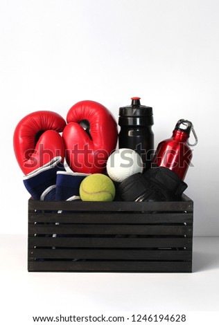 different sports items in the box: boxing gloves, dance shoes, racquets and tennis balls, water bottles. concept of healthy lifestyle
