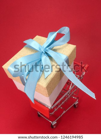 Shopping cart and big gift box on red background.